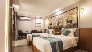 A hotel room with two beds, a desk, a chair, and a large decorative wall piece. - Thapae Twins Hotel (Chiang Mai)