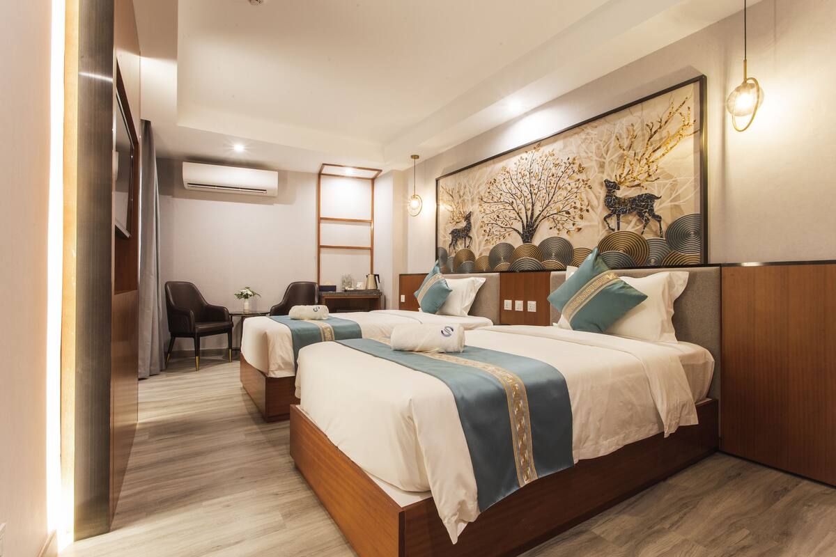 Ein Hotelzimmer mit zwei Betten, einem Schreibtisch, einem Stuhl und einem großen Wandbild.