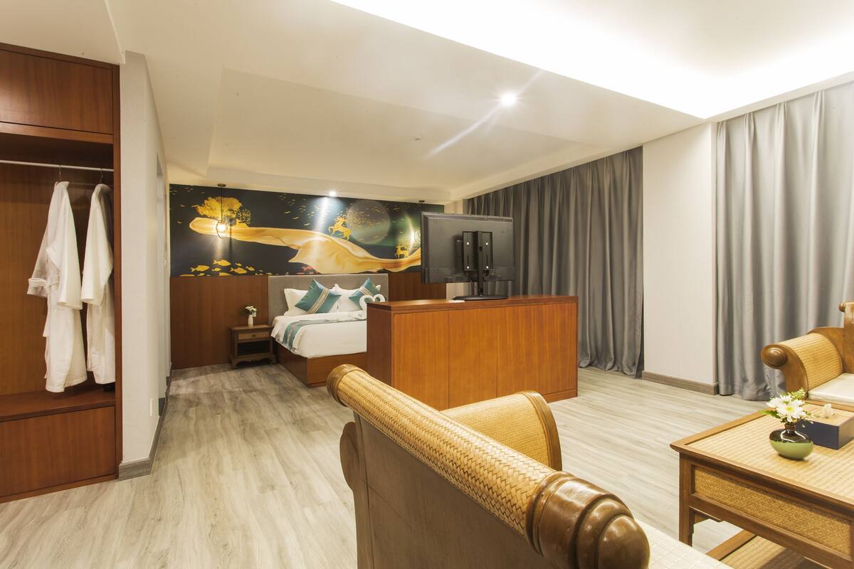 Ein Hotelzimmer mit Bett, Schreibtisch, Kleiderschrank und einem Gemälde an der Wand.