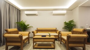 A living room with a sofa set, two armchairs, a coffee table, and two potted plants. - Thapae Twins Hotel (Chiang Mai)