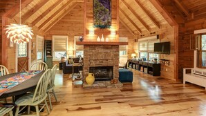 A spacious wooden cabin with a high ceiling, a fireplace, a dining area, and a television. - Respite at Big Canoe - Wood-burning fireplace, bright interiors, Wifi (Jasper)