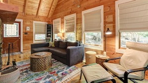 A cozy wooden cabin interior with a dark leather sofa, a round coffee table, and a beige armchair. - Respite at Big Canoe - Wood-burning fireplace, bright interiors, Wifi (Jasper)