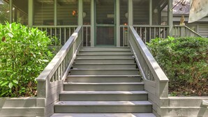 A staircase leading to a porch with a green door, surrounded by greenery. - Respite at Big Canoe - Wood-burning fireplace, bright interiors, Wifi (Jasper)
