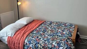 A bedroom with a bed, a floor lamp, and a wall with framed pictures.