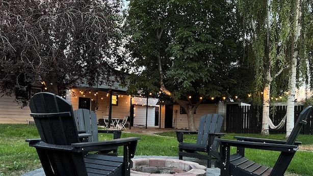 En uteplats med Adirondack-stolar, en eldstad och ljusslingor.