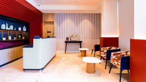 A modern reception area with a patterned counter, seating with colorful upholstery, and a decorative plant. - 7 Apple Hotel Jal Mahal Jaipur (Jaipur)