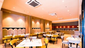 A spacious restaurant with high tables and yellow chairs, a bar area, and a modern interior design. - 7 Apple Hotel Jal Mahal Jaipur (Jaipur)