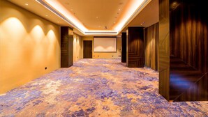 A hotel corridor with a carpeted floor, wooden panel walls, and a projection screen at the end. - 7 Apple Hotel Jal Mahal Jaipur (Jaipur)