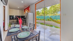 A dining area with a view of a garden and a hammock. - Villas Mapache del Caribe (Cahuita)