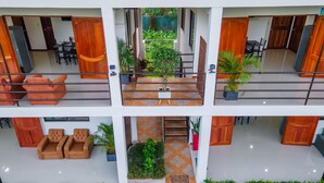 A multi-level hotel with a central atrium, outdoor seating, and potted plants. - Villas Mapache del Caribe (Cahuita)
