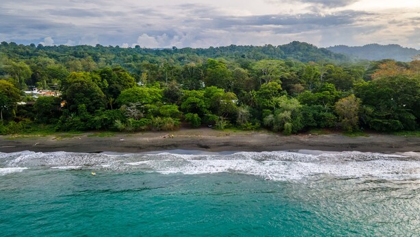 A coastal landscape with a beach, ocean, and forested hills in the background. - Villas Mapache del Caribe (Cahuita)