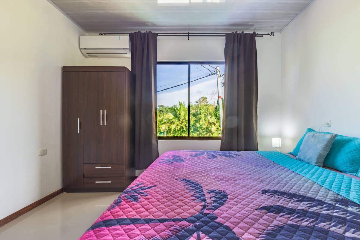 Ein Schlafzimmer mit einem großen Bett, einem Kleiderschrank und einem Fenster mit Vorhängen.