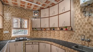 Une cuisine dotée d’un comptoir incurvé, de meubles de couleur beige, d’une fenêtre et d’une cuisinière encastrée.