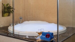 A bathtub filled with bubbles, a glass of wine, and a towel with a flower on a tray. - The Orchard Farm, Manesar- Luxury Pet- Friendly Farm with private pool & Jacuzzi (Para)