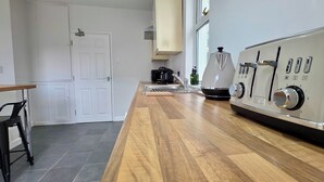 Una cocina moderna con encimera de madera, electrodomésticos de acero inoxidable y una cafetera.