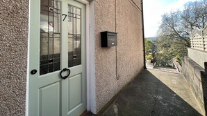 A building with a textured exterior, a white door with a heart-shaped knocker, and a mailbox labeled "POST". - Brecon View by Switchback Stays (Newport)