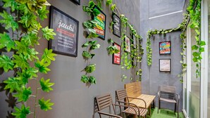 A room with a grey wall, wooden chairs, a small table, and green plants. - City Biz Residence (Jakarta)