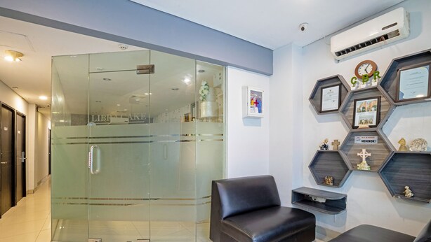A reception area with a glass door, black leather seating, and hexagonal shelves with certificates and figurines. - City Biz Residence (Jakarta)