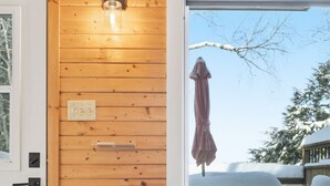 A cozy room with a grey sofa, a small white table with a plant, and a wooden wall. - Lakeside Retreat with Hot Tub (Windsor)