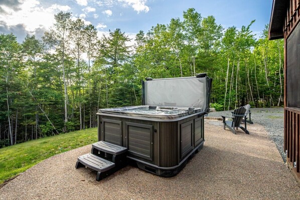 An outdoor hot tub with steps, surrounded by a gravel area and trees. - Treeside Retreat with Hot tub (Windsor)