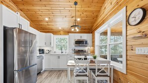A modern kitchen with white cabinets, stainless steel appliances, and a wooden ceiling. - Treeside Retreat with Hot tub (Windsor)