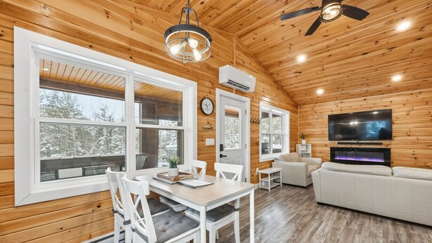 A cozy cabin interior with a dining area, a living room, and a fireplace. - Treeside Retreat with Hot tub (Windsor)