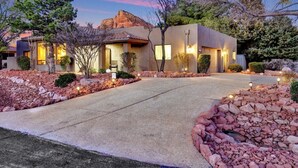 A modern two-story house with a stone facade, a driveway, and landscaped gardens.