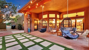 A patio with hanging chairs, a swing chair, and a stone pathway.