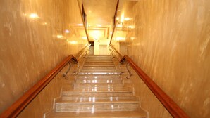 Una escalera de mármol con barandillas de madera que conduce a una puerta en la parte superior.