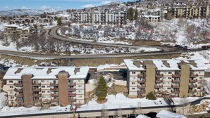 Ett högt hotell med flera balkonger, ett parkeringsgarage och utsikt över ett snötäckt landskap med berg i bakgrunden.