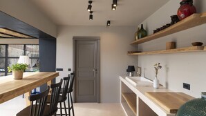 Una cocina moderna con encimeras de madera, sillas negras e iluminación colgante.