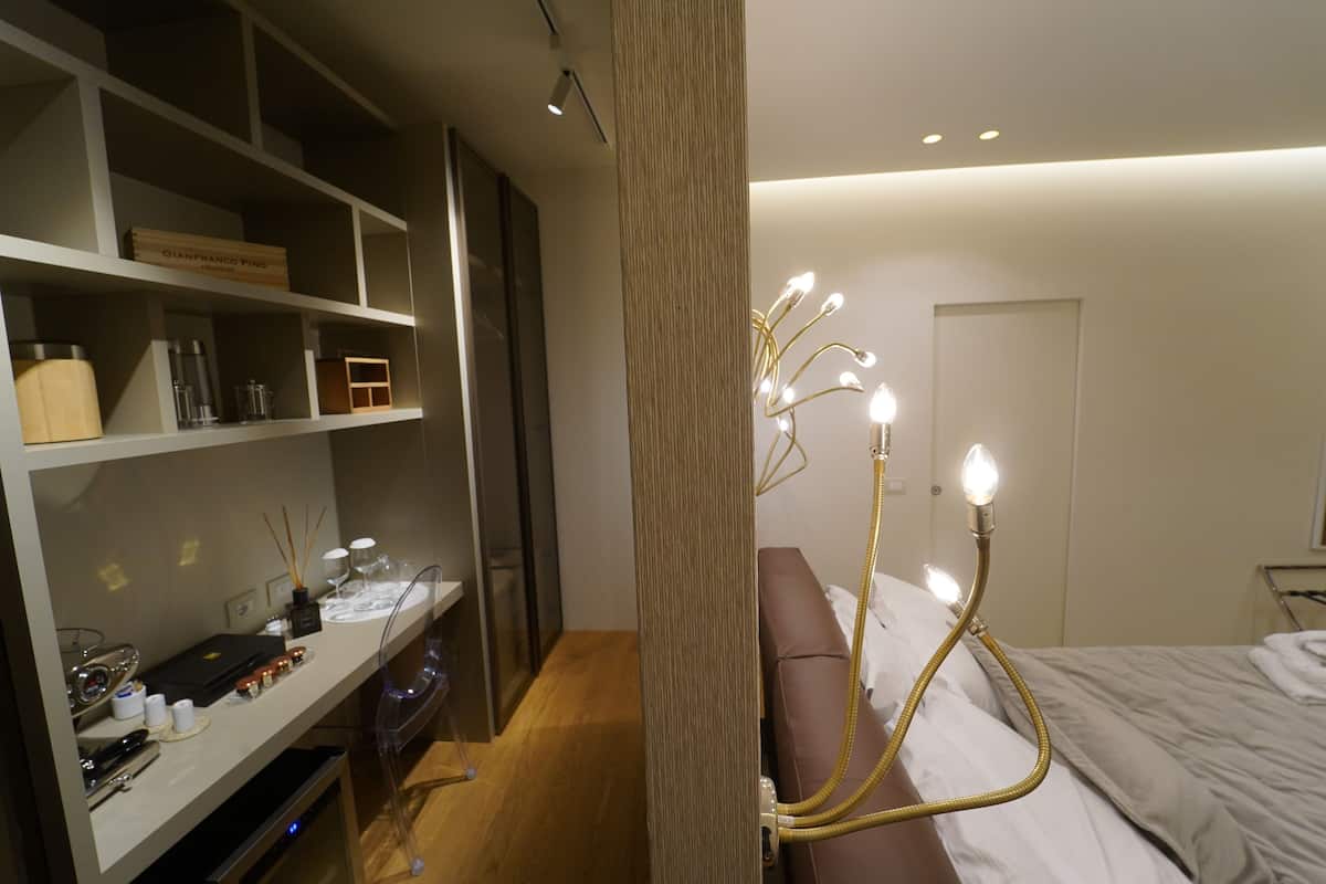 A modern bedroom with a bed, a bedside table, a wardrobe, and a unique chandelier.