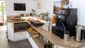 A modern kitchen with a coffee machine, fruit, and breakfast items.
