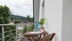 A wooden deck with a table and chairs, a potted plant, and a bottle of water. - Pension Klein (Bad Laasphe)