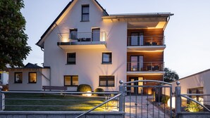 A modern multi-story building with balconies, a gated entrance, and a well-maintained lawn. - Pension Klein (Bad Laasphe)