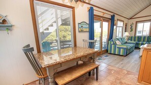 A cozy interior with a dining area, a bench, a sofa, and a view of the outdoors. - Oceanside, Private Pool, Hot Tub, MIL Suite, KH529, Sea Turtle Sunrise (Kitty Hawk)