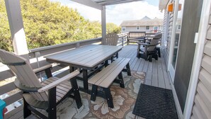 An outdoor deck with picnic tables and chairs, a wooden bench, and a doormat. - Oceanside, Private Pool, Hot Tub, MIL Suite, KH529, Sea Turtle Sunrise (Kitty Hawk)