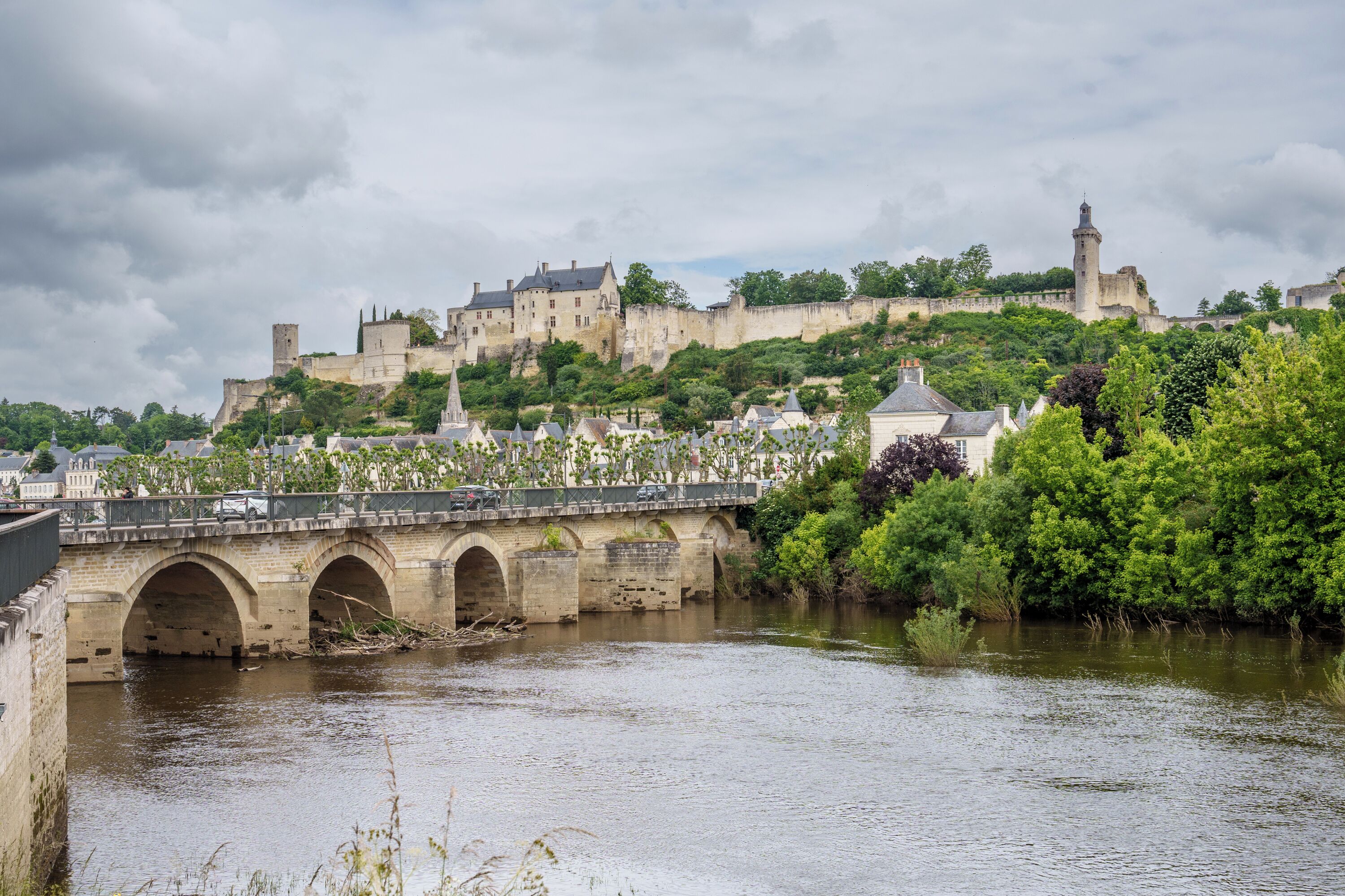 Eine Steinbrücke über einem Fluss, im Hintergrund ein Schloss und ein Turm.