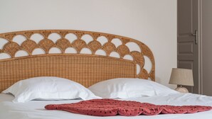 A bed with a woven headboard, white pillows, and a red blanket. - Pretty town house in the heart of Chinon + garden 6 p. (Chinon)
