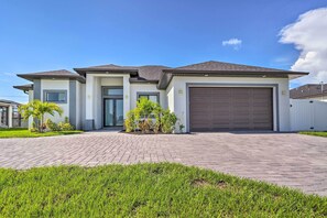 Enter a serene home surrounded by lush landscaping and mature trees, with a spacious driveway and two-car garage.