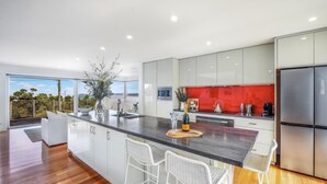 A modern kitchen with a large island, white cabinetry, and a red backsplash.