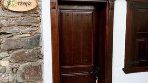 Una porta de fusta amb un tancatge metàl·lic, encaixada en una paret blanca amb una base de pedra. Un senyal de fusta sobre la porta diu "Nerrez".