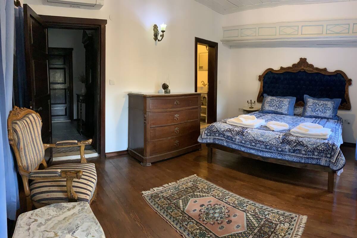 A bedroom with a wooden bed, a nightstand, a dresser, a chair, and a patterned rug.