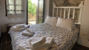 Un dormitori amb un llit, una tauleta de nit i una finestra amb cortines.