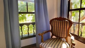 Una habitació amb una cadira i un taulell de fusta, i una finestra amb cortines blaves.