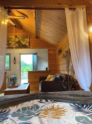 Cozy room with a sloped ceiling, featuring a central bed, table, and chair.