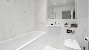 A modern bathroom with a freestanding bathtub, a vanity with a mirror, and a toilet. - Elliot Oliver - Cosy 2 Bedroom Town Centre Apartment (Cheltenham)