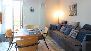 Una sala de estar con un sofá, una mesa de comedor, sillas, un reloj y un adorno en la pared.