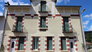 Un edificio de dos plantas con fachada simétrica, que presenta un balcón central, ventanas uniformemente distribuidas y una pequeña entrada con puerta.