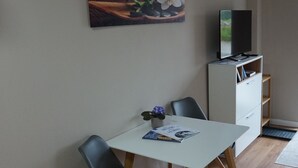 A dining area with a white table, two chairs, a small potted plant, and a painting on the wall. - HochgratBlick.modern.cozy.relaxed (Argenbühl)